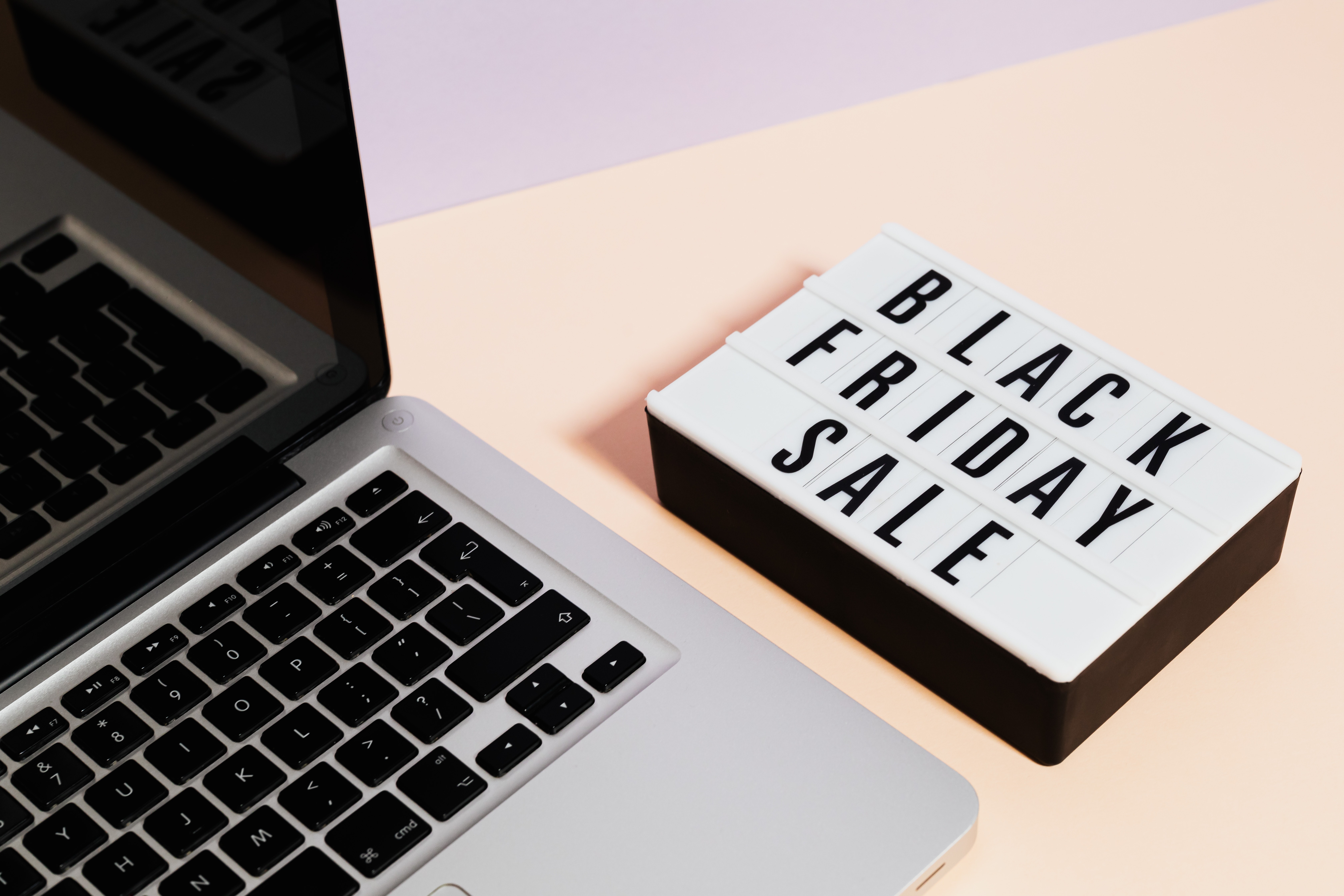 Laptop on a table sitting next to a sign that says 'Black Friday Sale' 