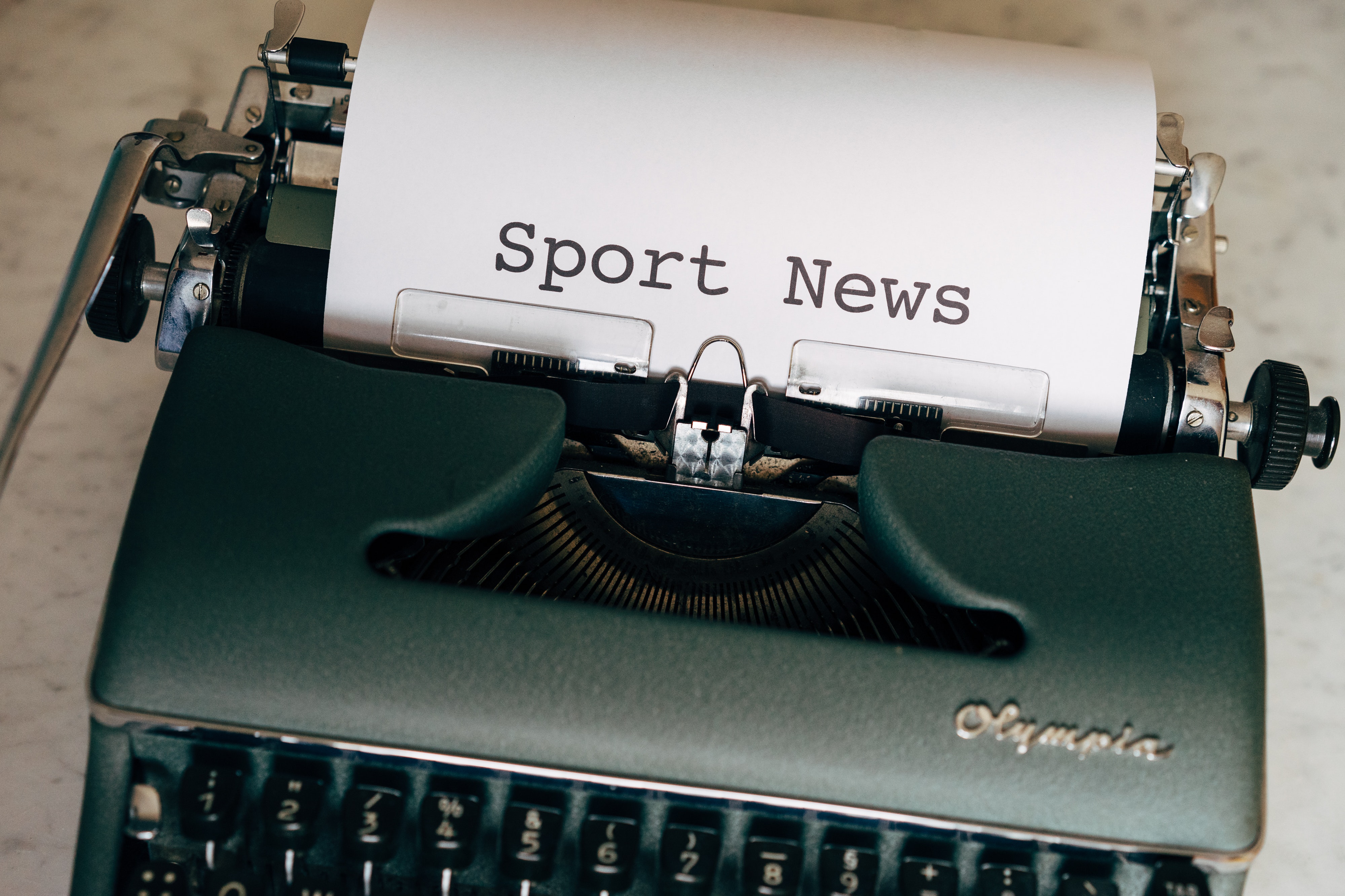 A typewriter typing on a document that says 'Sport News' 