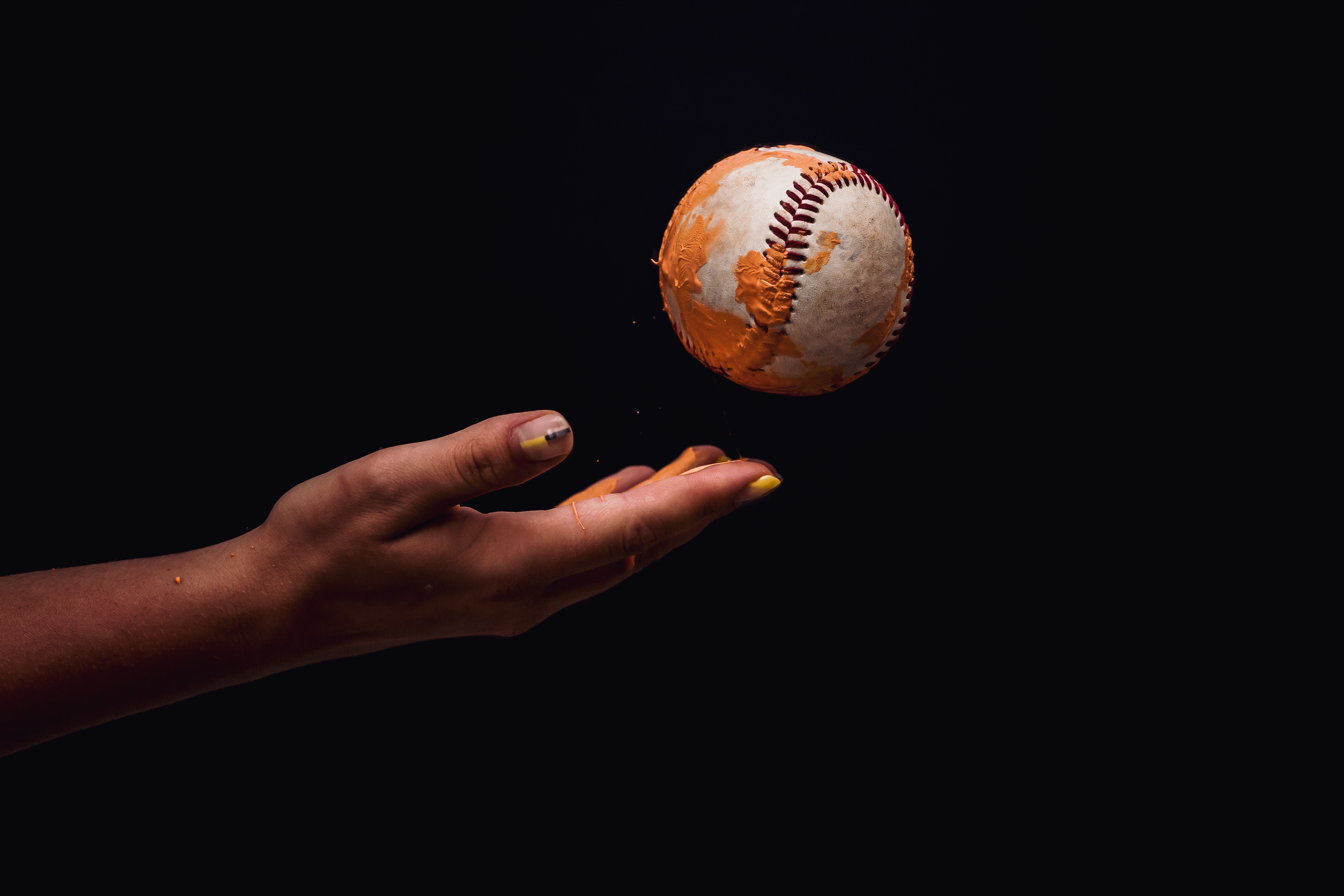 Hand catching a baseball with orange paint